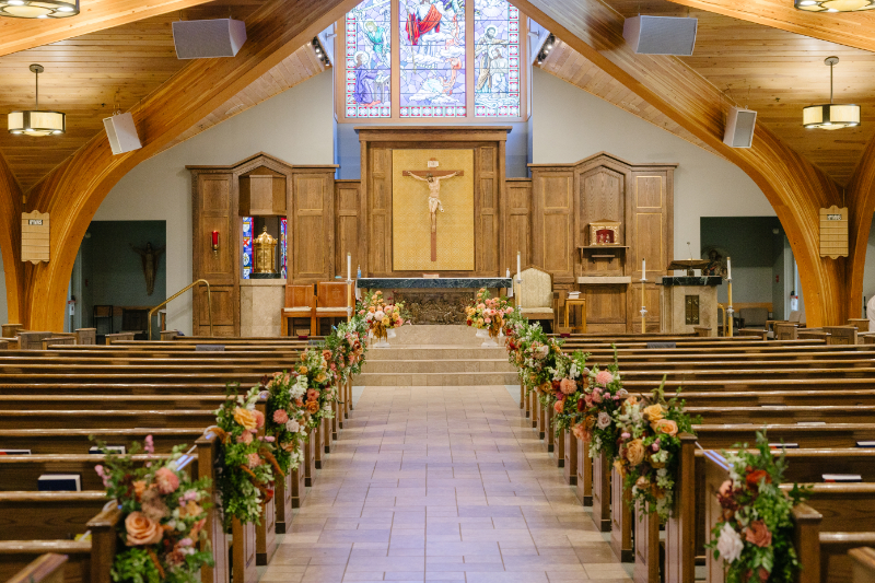 Church wedding ceremony aisle decorated with lush floral arrangements leading to the altar before a Jackson Hole wedding ceremony.