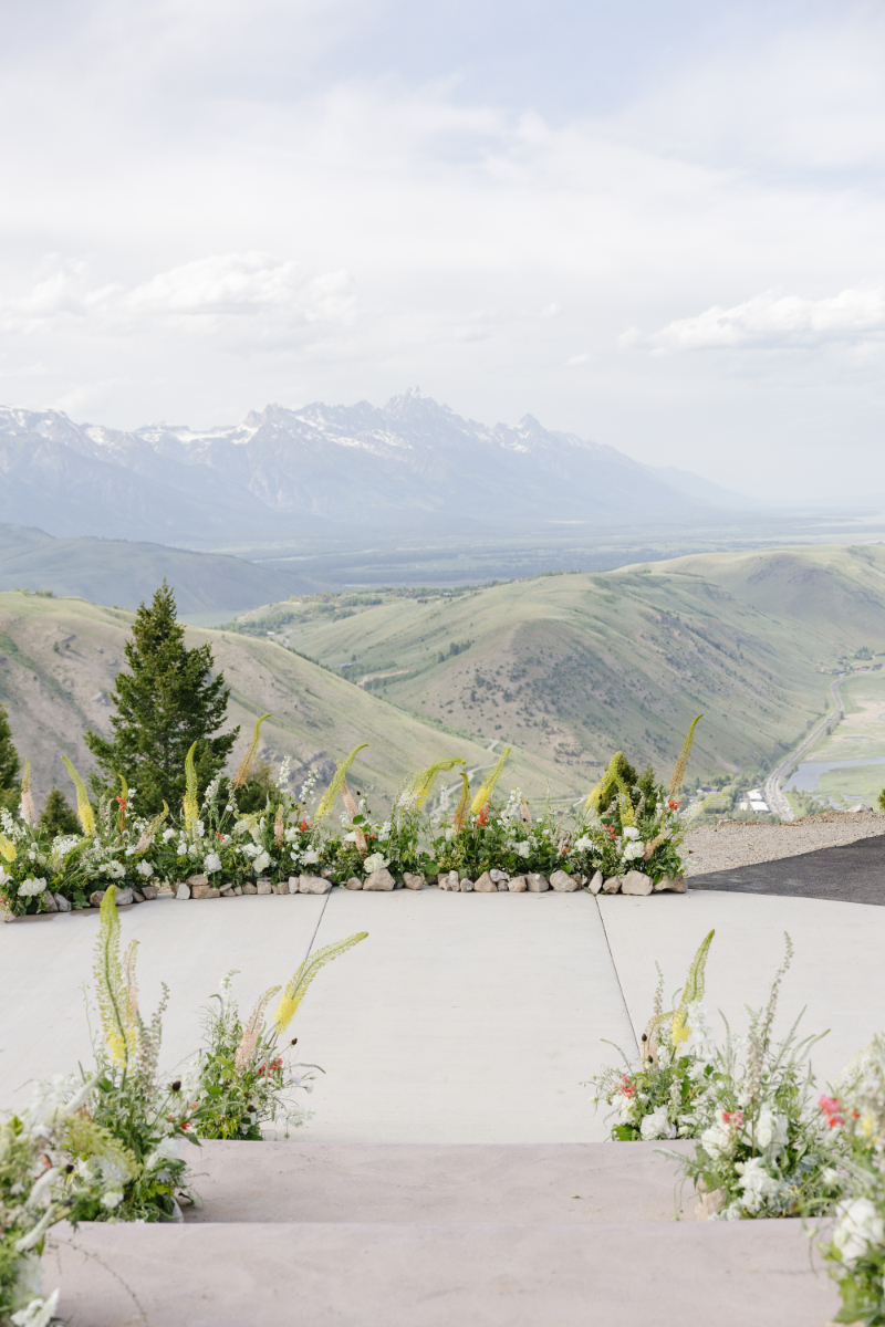 Mountain-view ceremony space overlooking the Teton Range with floral-lined aisle at a Jackson Hole wedding venue.