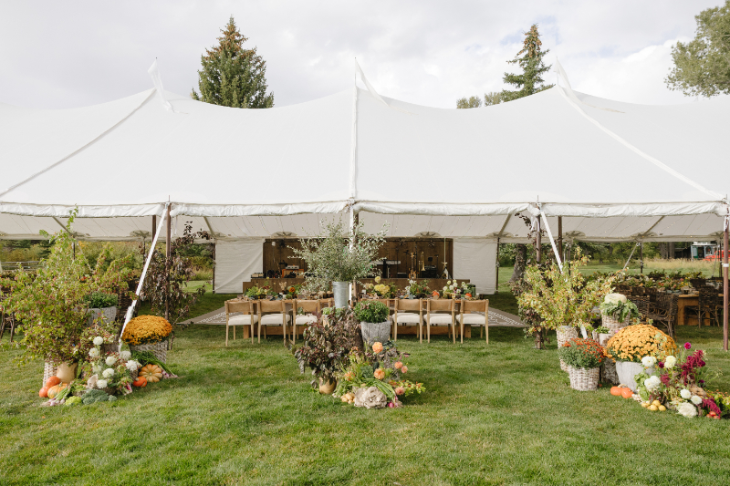 Outdoor wedding reception tent surrounded by colorful fall floral arrangements in Jackson Hole