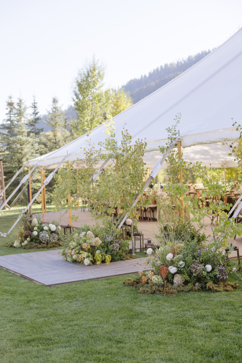 Outdoor tent reception with lush floral arrangements and mountain scenery for a Jackson wedding.