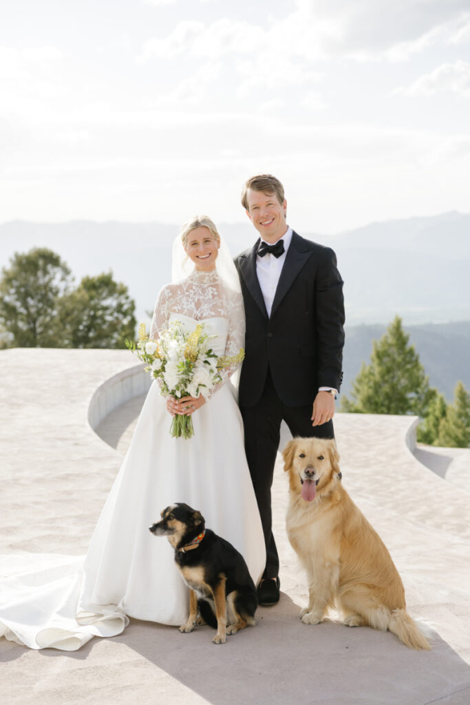 Bride and groom posing with their two dogs against mountain views during their Jackson wedding.