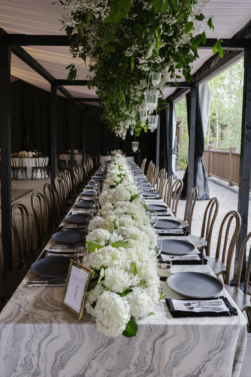 Elegant Jackson Hole wedding reception table with white hydrangeas, greenery, and hanging candlelight
