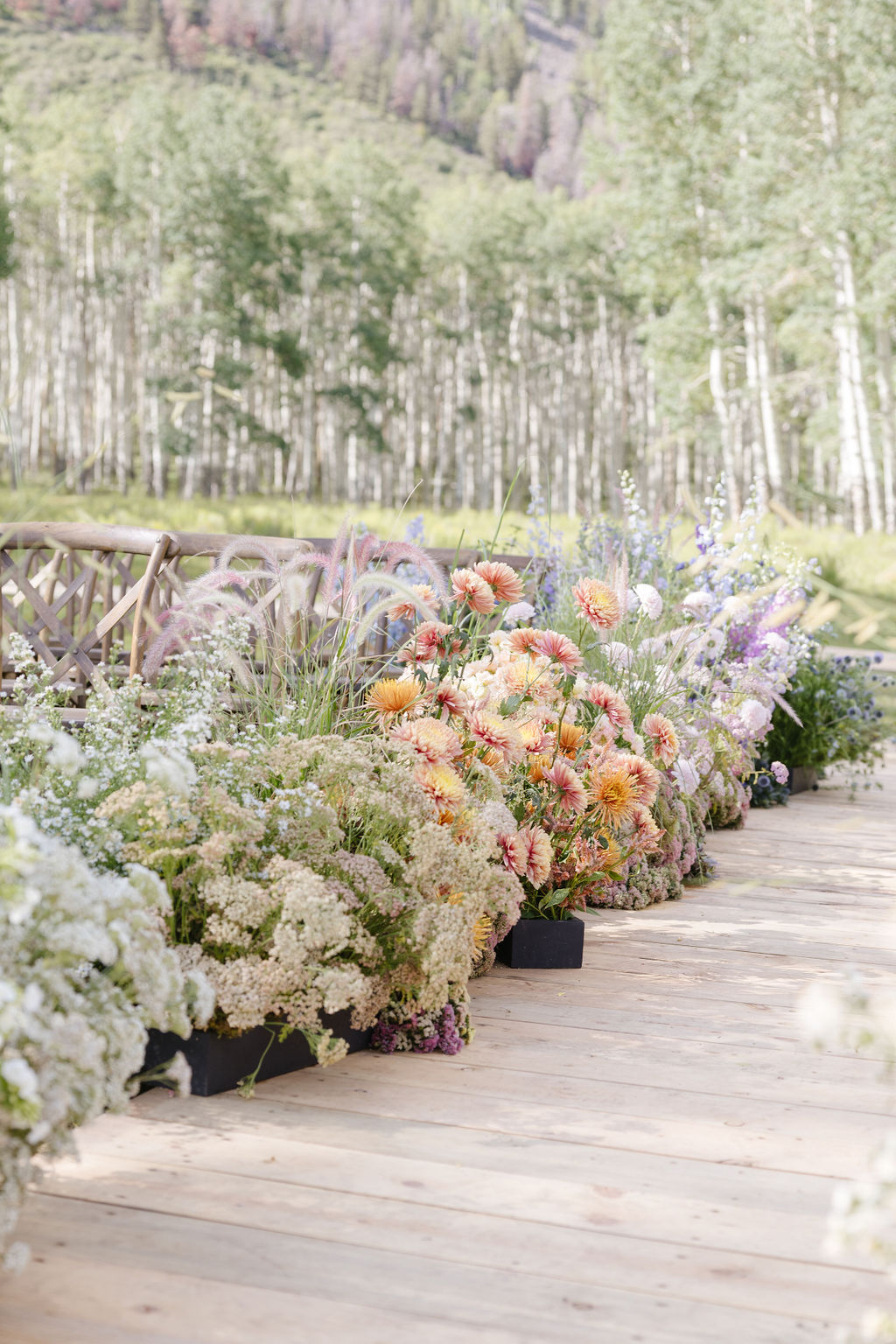 Colorful wedding flowers lining an outdoor ceremony aisle in Jackson Hole