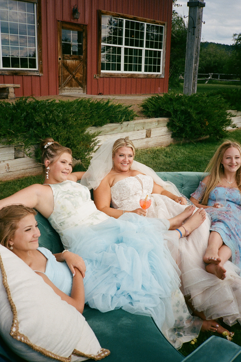 Bride relaxing with friends on an outdoor lounge during a colorful Western wedding celebration