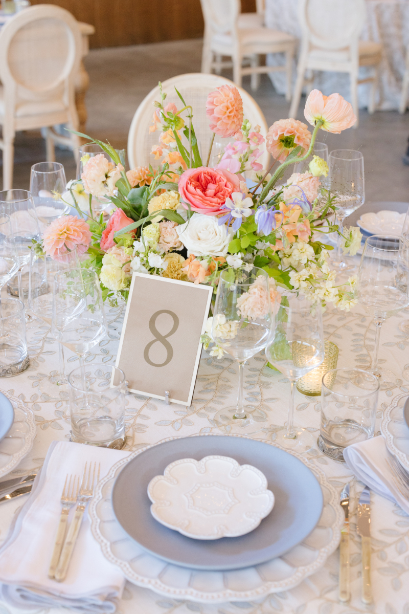 Colorful wedding floral centerpiece with coral, blush, lavender, and white flowers on an elegant reception table
