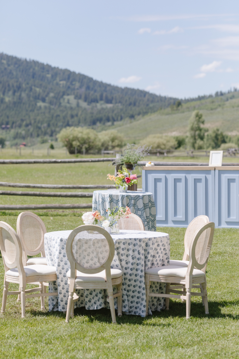 Outdoor Jackson Hole wedding reception with blue patterned linens, floral arrangements, and mountain views