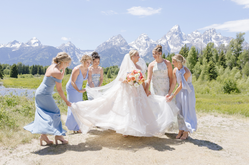 Bride with bridesmaids in pastel dresses during wedding portraits with the Grand Tetons behind them
